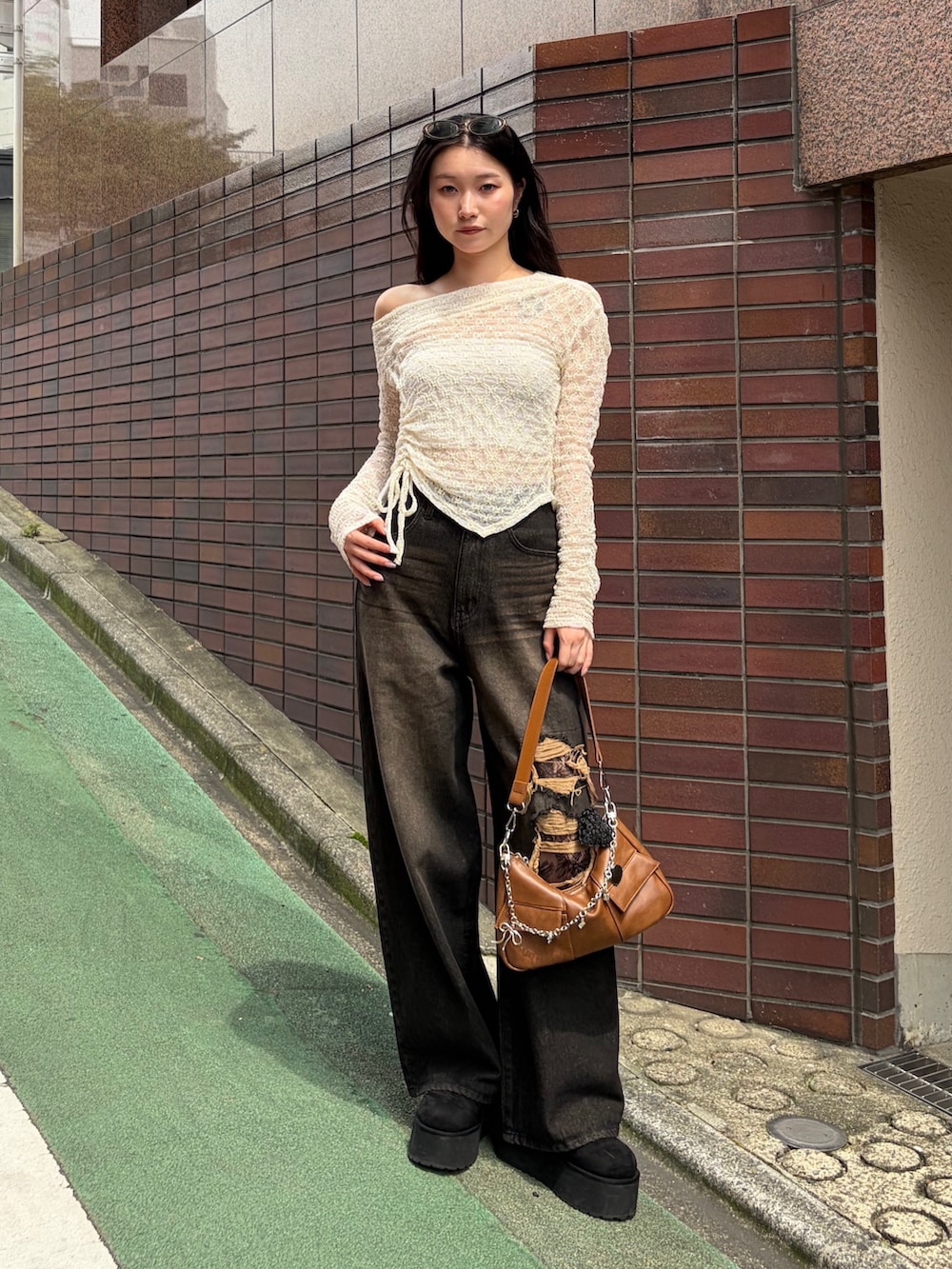 ブラウン系のショルダーバッグ、ホワイト系のTシャツ/カットソー、ブラック系のデニムパンツを着用したレディースの秋コーディネートの2枚目の写真