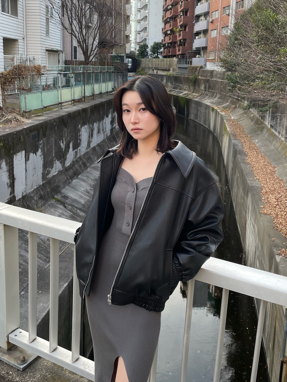 グレー系のワンピース、ブラック系のブルゾン、ブラック系のブーツを着用したレディースの冬コーディネートの4枚目の写真