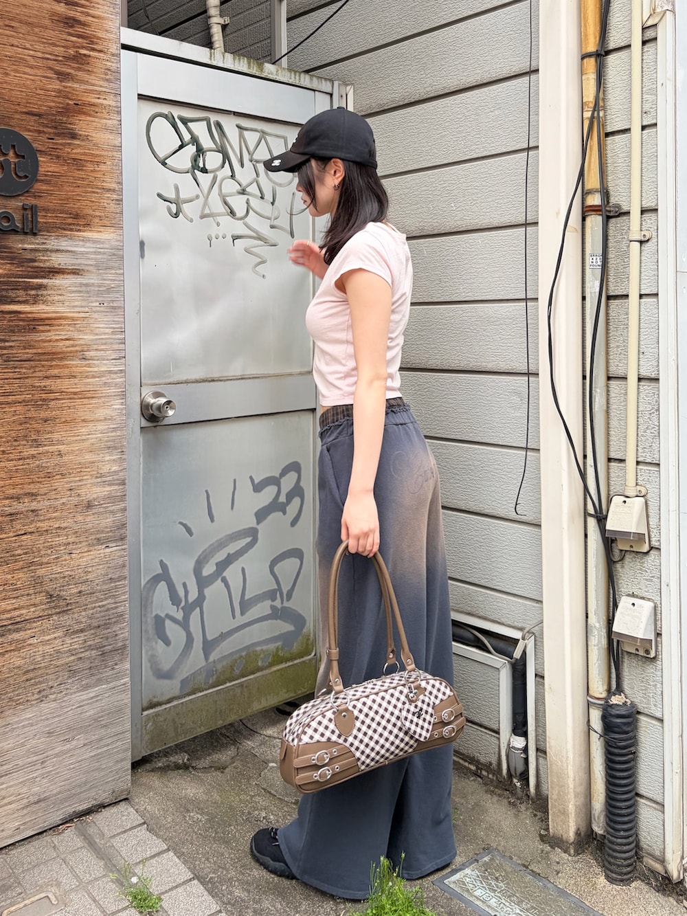 ブラウン系のハンドバッグ、ピンク系のTシャツ/カットソー、ブルー系のスウェットパンツを着用したレディースの春コーディネートの3枚目の写真