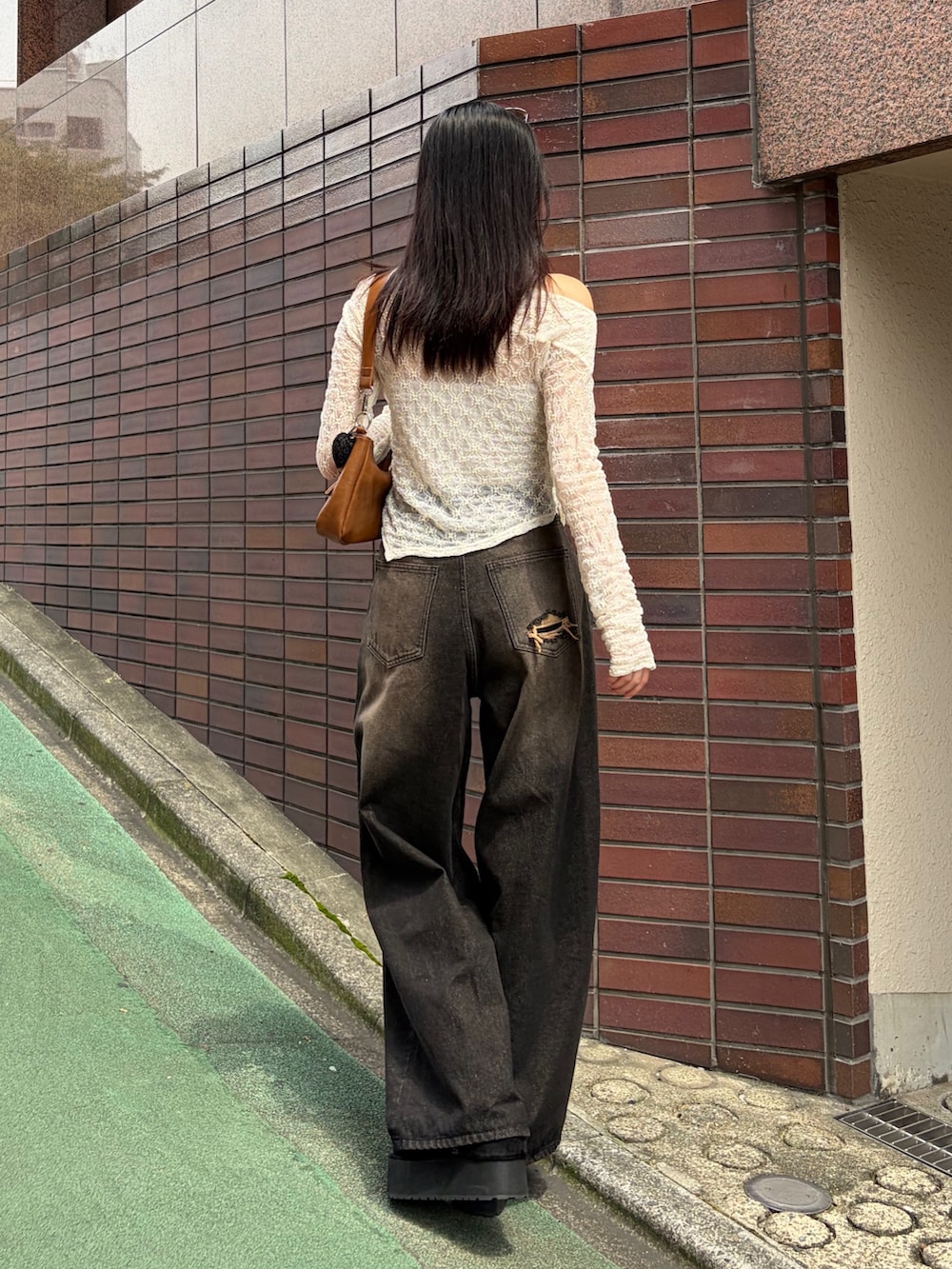 ブラウン系のショルダーバッグ、ホワイト系のTシャツ/カットソー、ブラック系のデニムパンツを着用したレディースの秋コーディネートの4枚目の写真