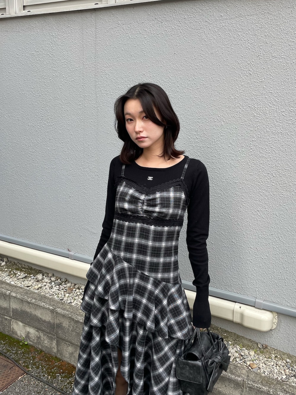 ブラック系のニット/セーター、ブラック系のワンピース、ブラック系のハンドバッグを着用したレディースの冬コーディネートの5枚目の写真