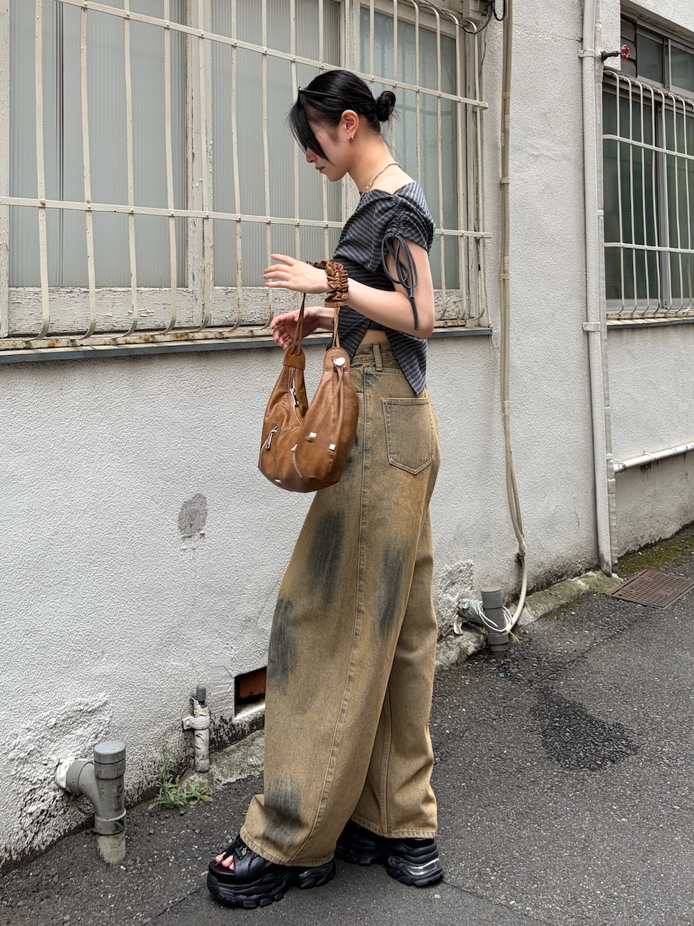 グレー系のTシャツ/カットソー、ブラウン系のショルダーバッグ、ベージュ系のデニムパンツを着用したレディースの夏コーディネートの2枚目の写真