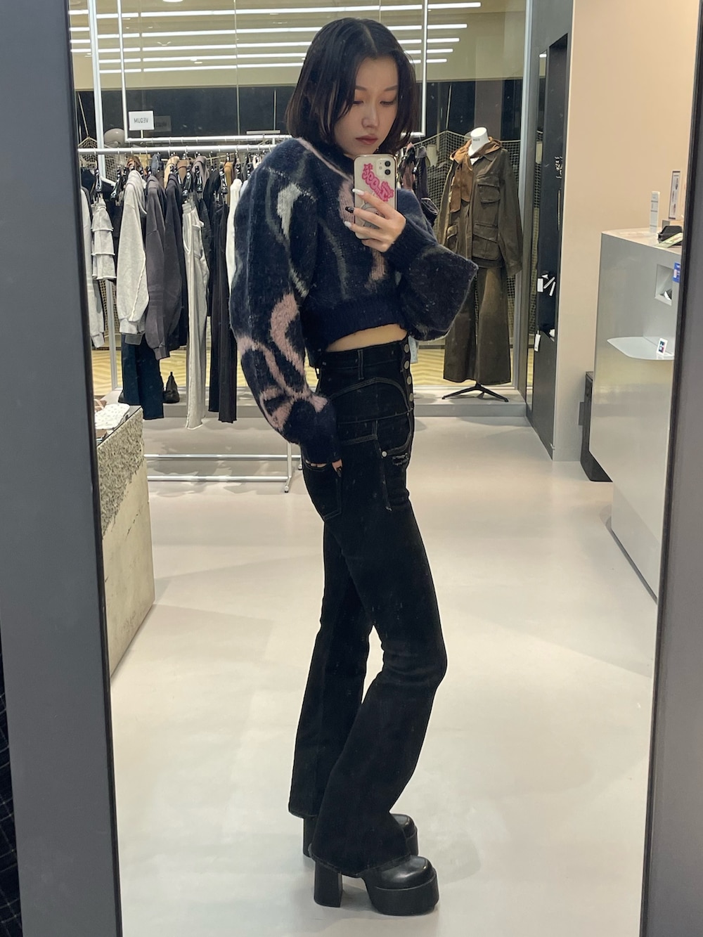 ブルー系のニット/セーター、ブラック系のデニムパンツ、ブラック系のブーツを着用したレディースの秋コーディネートの2枚目の写真