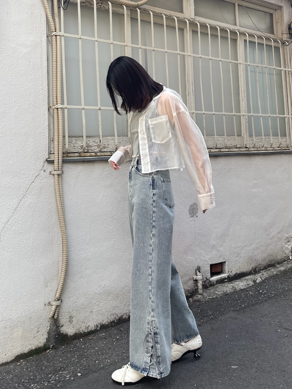 ブルー系のタンクトップ、ブルー系のデニムパンツ、ホワイト系のスニーカーを着用したレディースの春コーディネートの2枚目の写真