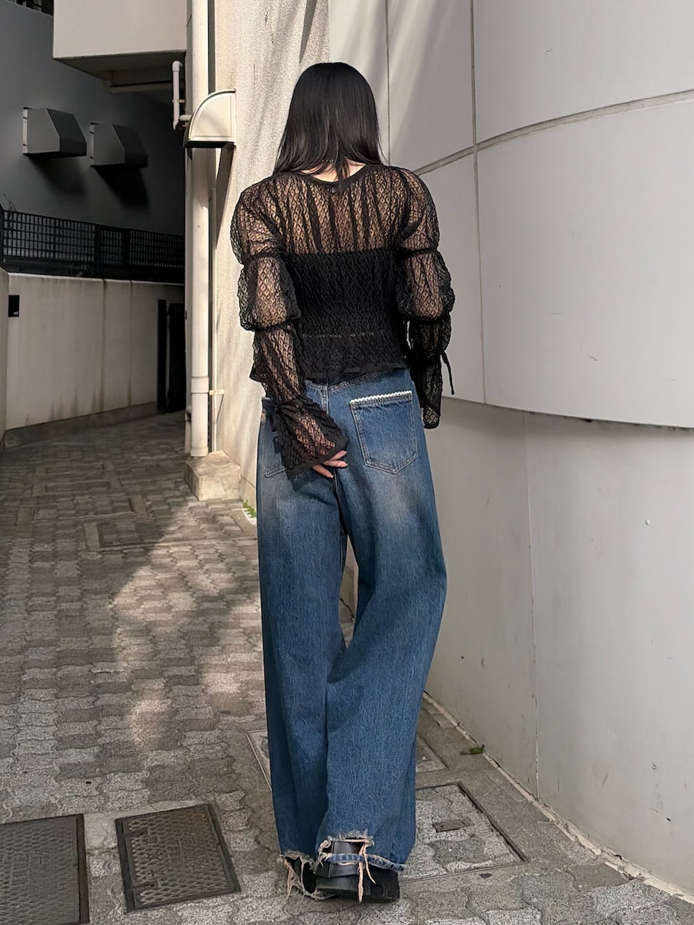 ブラック系のニット/セーター、ブルー系のデニムパンツ、ブラック系のブーツを着用したレディースの春コーディネートの4枚目の写真