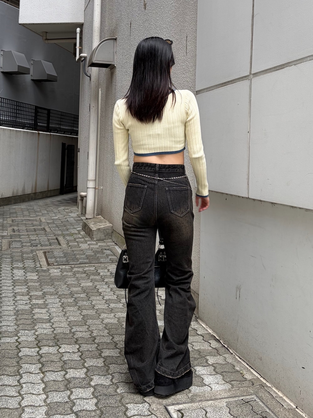 ホワイト系のニット/セーター、ブラック系のショルダーバッグ、ブラック系のデニムパンツを着用したレディースの秋コーディネートの3枚目の写真
