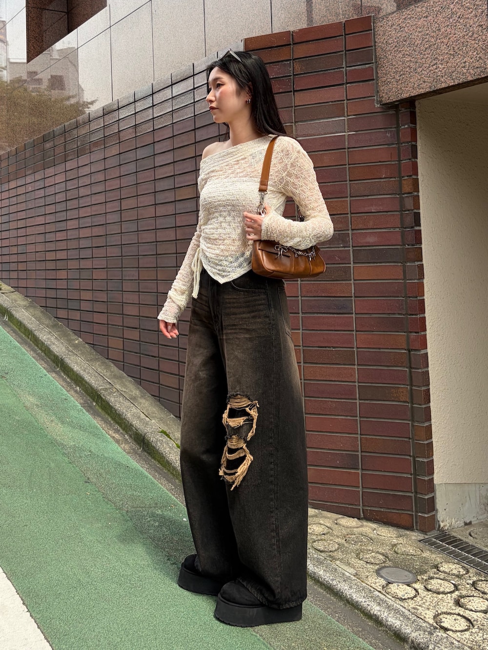 ブラウン系のショルダーバッグ、ホワイト系のTシャツ/カットソー、ブラック系のデニムパンツを着用したレディースの秋コーディネートの3枚目の写真
