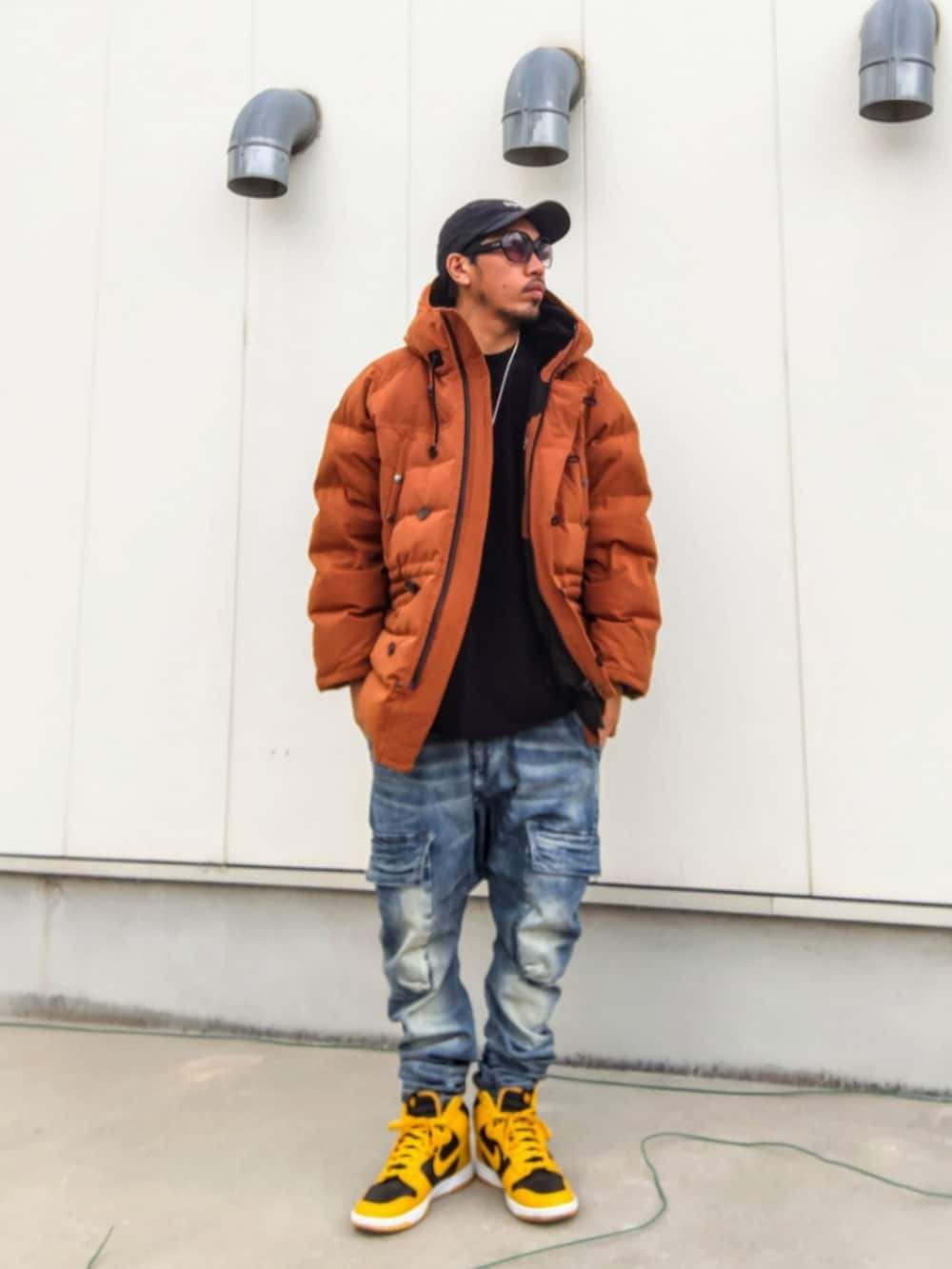 イエロー系のダウンジャケット/コート、ブラック系のTシャツ/カットソー、ブルー系のデニムパンツを着用したメンズの冬コーディネートの2枚目の写真