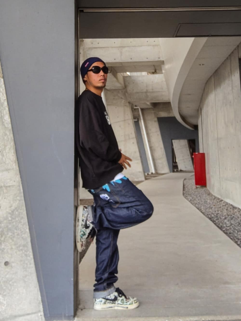 ブラック系のスウェット、ブルー系のデニムパンツ、ホワイト系のスニーカーを着用したメンズの秋コーディネートの2枚目の写真