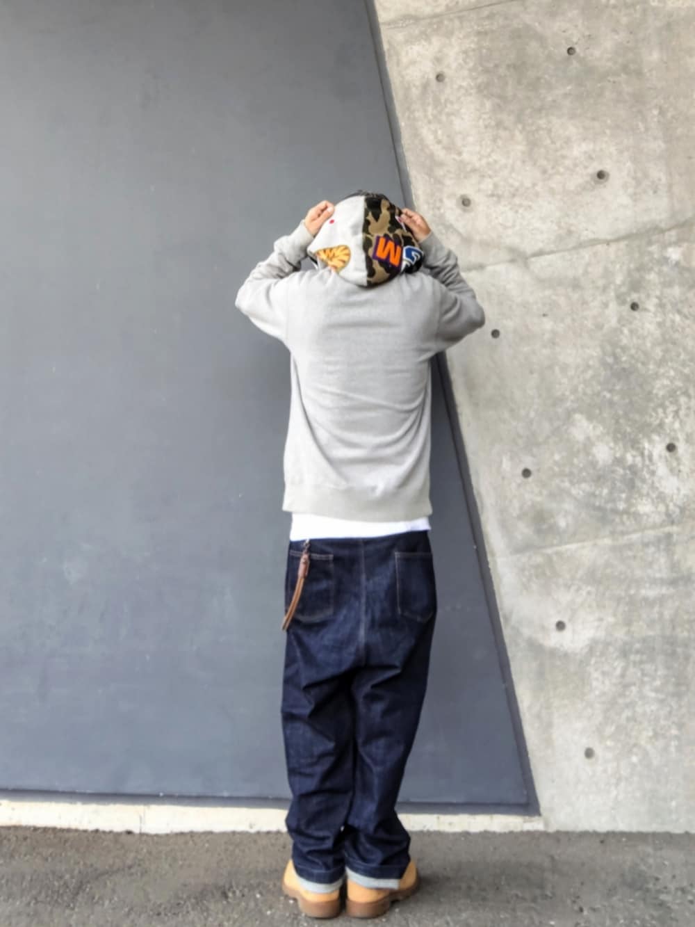 グレー系のパーカー、ブルー系のデニムパンツ、イエロー系のブーツを着用したメンズの春コーディネートの2枚目の写真