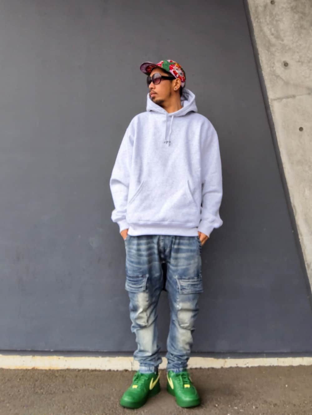 グレー系のパーカー、ブルー系のデニムパンツ、グリーン系のスニーカーを着用したメンズの冬コーディネートの2枚目の写真