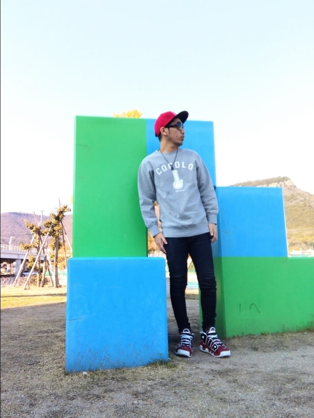 グレー系のスウェット、ブルー系のデニムパンツ、レッド系のスニーカーを着用したメンズの春コーディネートの2枚目の写真