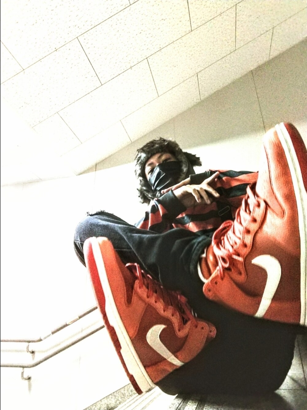 オレンジ系のニット/セーター、ブラック系のサロペット/オーバーオール、オレンジ系のスニーカーを着用したメンズの秋コーディネートの2枚目の写真