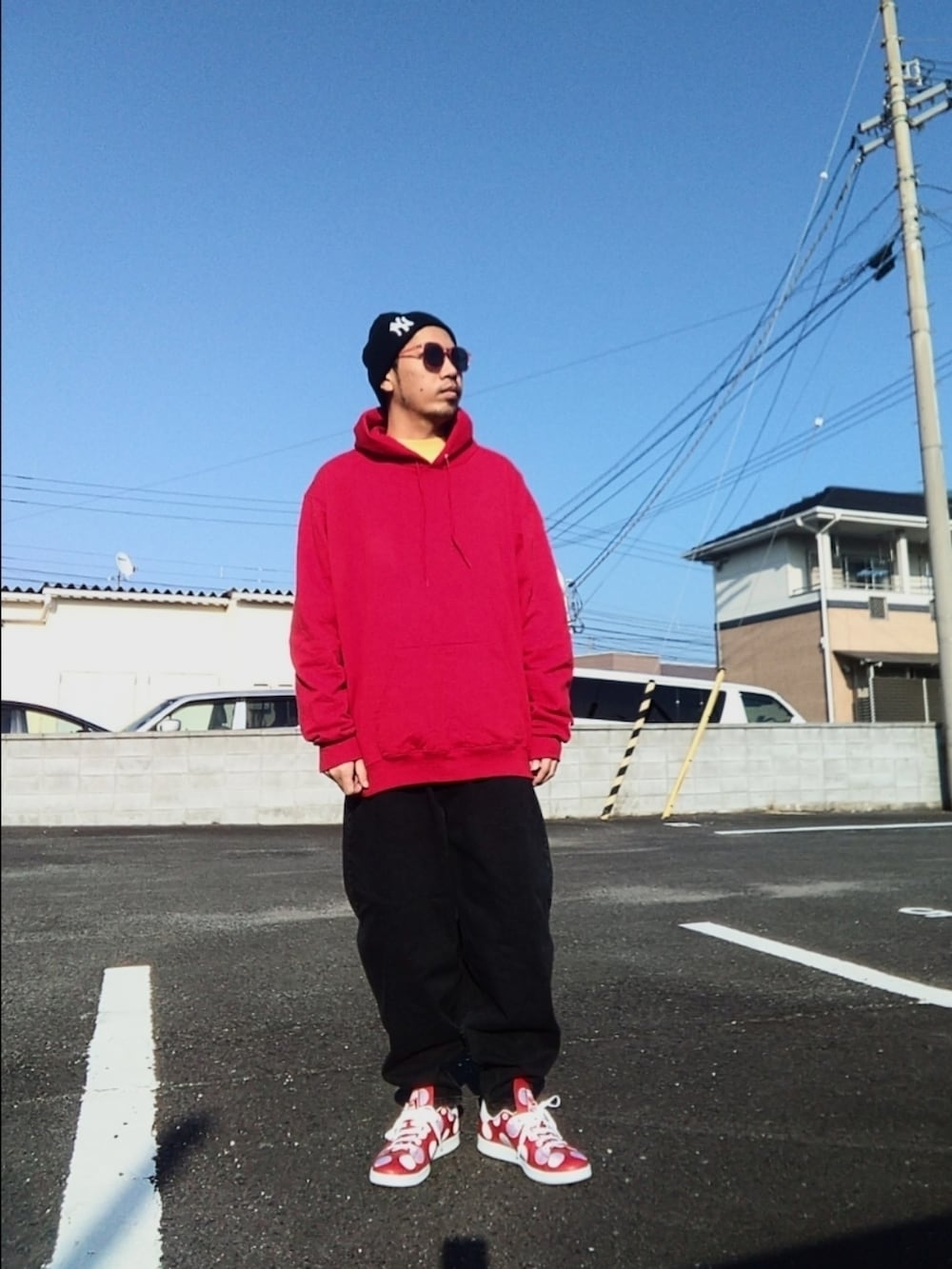 レッド系のパーカー、ブラック系のデニムパンツ、レッド系のスニーカーを着用したメンズの冬コーディネートの2枚目の写真
