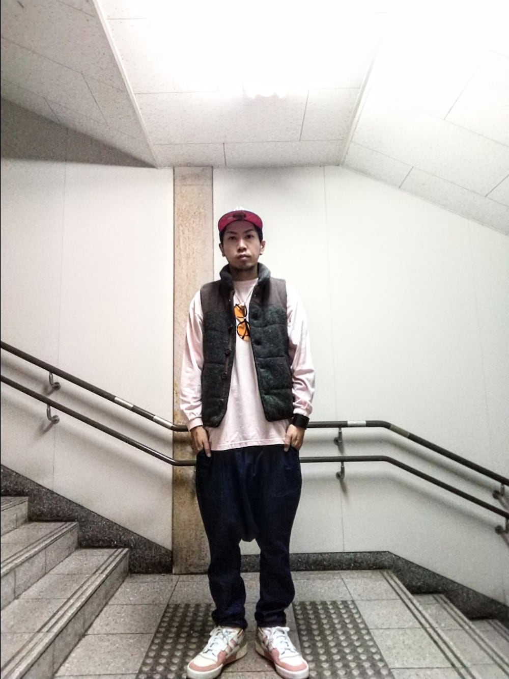 グレー系のベスト、ピンク系のTシャツ/カットソー、ブルー系のデニムパンツを着用したメンズの秋コーディネートの3枚目の写真