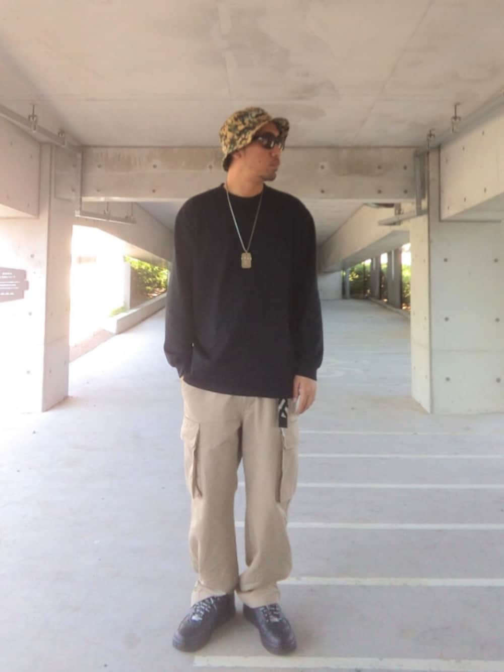 ブラック系のTシャツ/カットソー、ベージュ系のカーゴパンツ、ブラック系のスニーカーを着用したメンズの春コーディネートの2枚目の写真