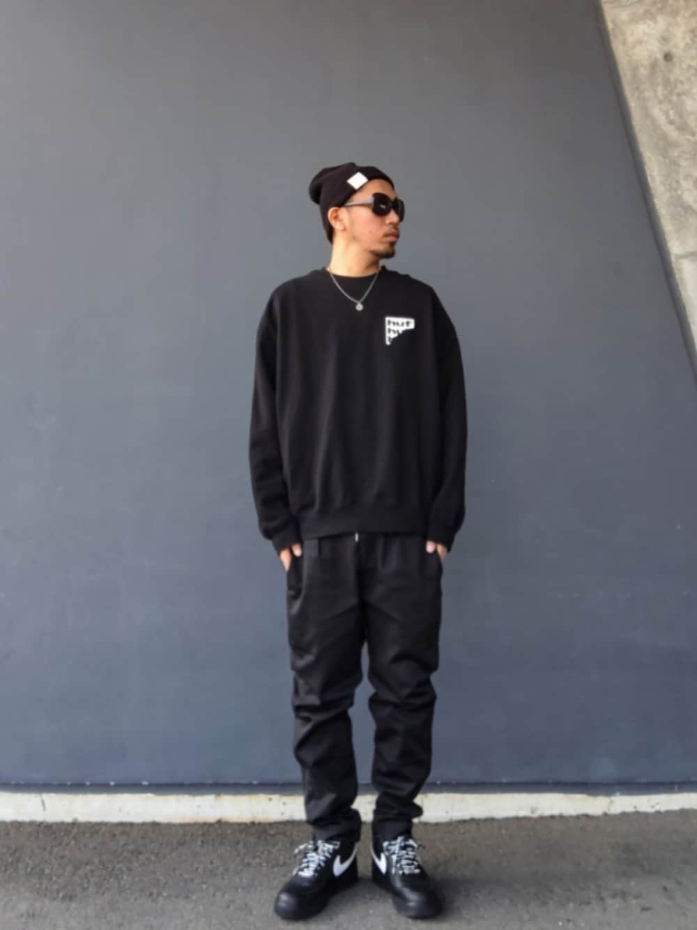 ブラック系のスウェット、ブラック系のパンツ、ブラック系のスニーカーを着用したメンズの春コーディネートの2枚目の写真