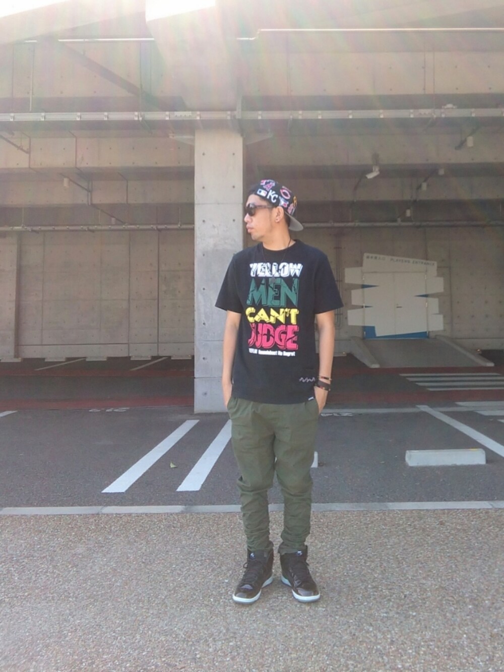 ブラック系のTシャツ/カットソー、グリーン系のパンツ、ブラック系のスニーカーを着用したメンズの夏コーディネートの3枚目の写真