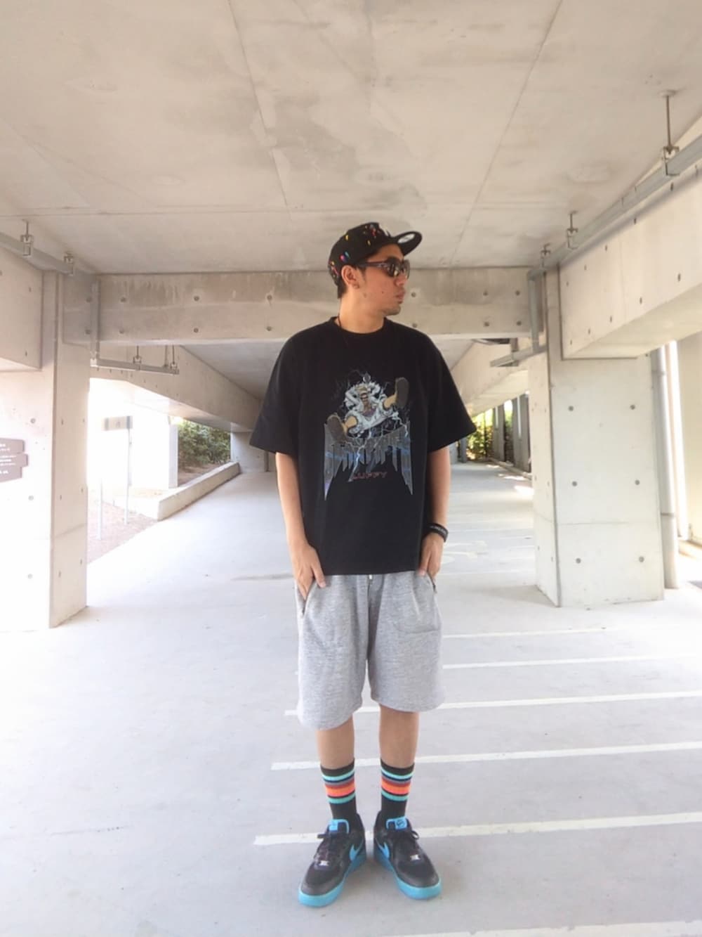 ブラック系のTシャツ/カットソー、グレー系のその他パンツ、ブルー系のスニーカーを着用したメンズの夏コーディネートの2枚目の写真