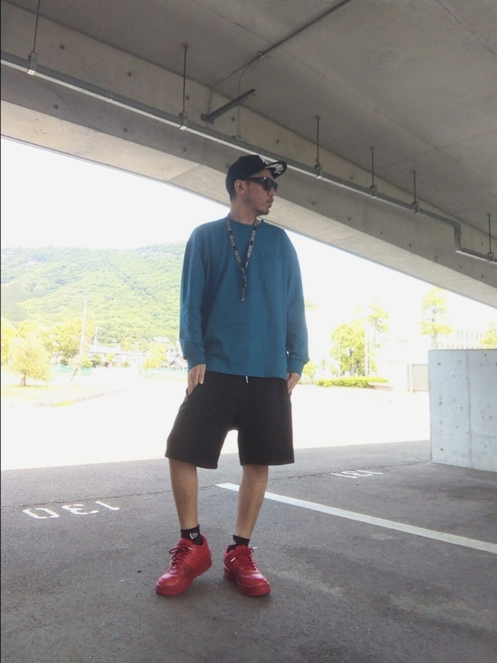 レッド系のスニーカー、ブルー系のトップス、ブラック系のその他パンツを着用したメンズの春コーディネートの3枚目の写真