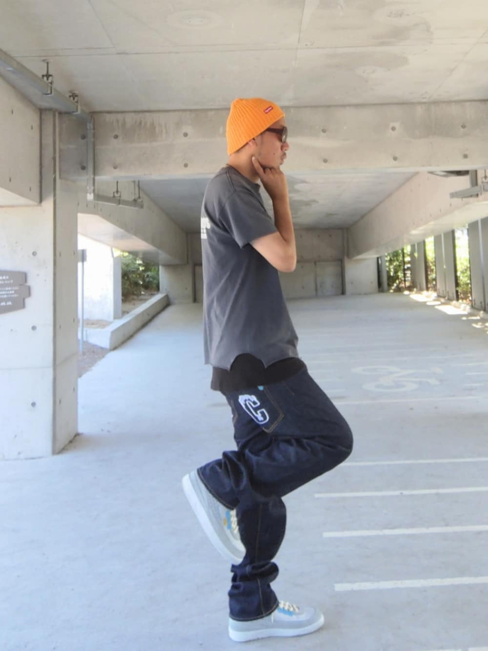 ブラック系のタンクトップ、ブルー系のデニムパンツ、グレー系のスニーカーを着用したメンズの夏コーディネートの2枚目の写真