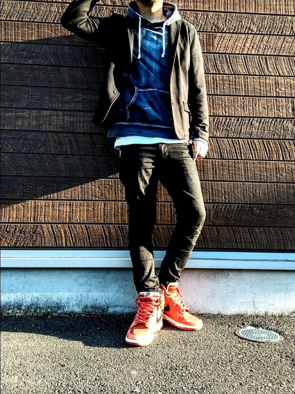 ブルー系のパーカー、ブラック系のデニムパンツ、オレンジ系のスニーカーを着用したメンズの秋コーディネートの3枚目の写真