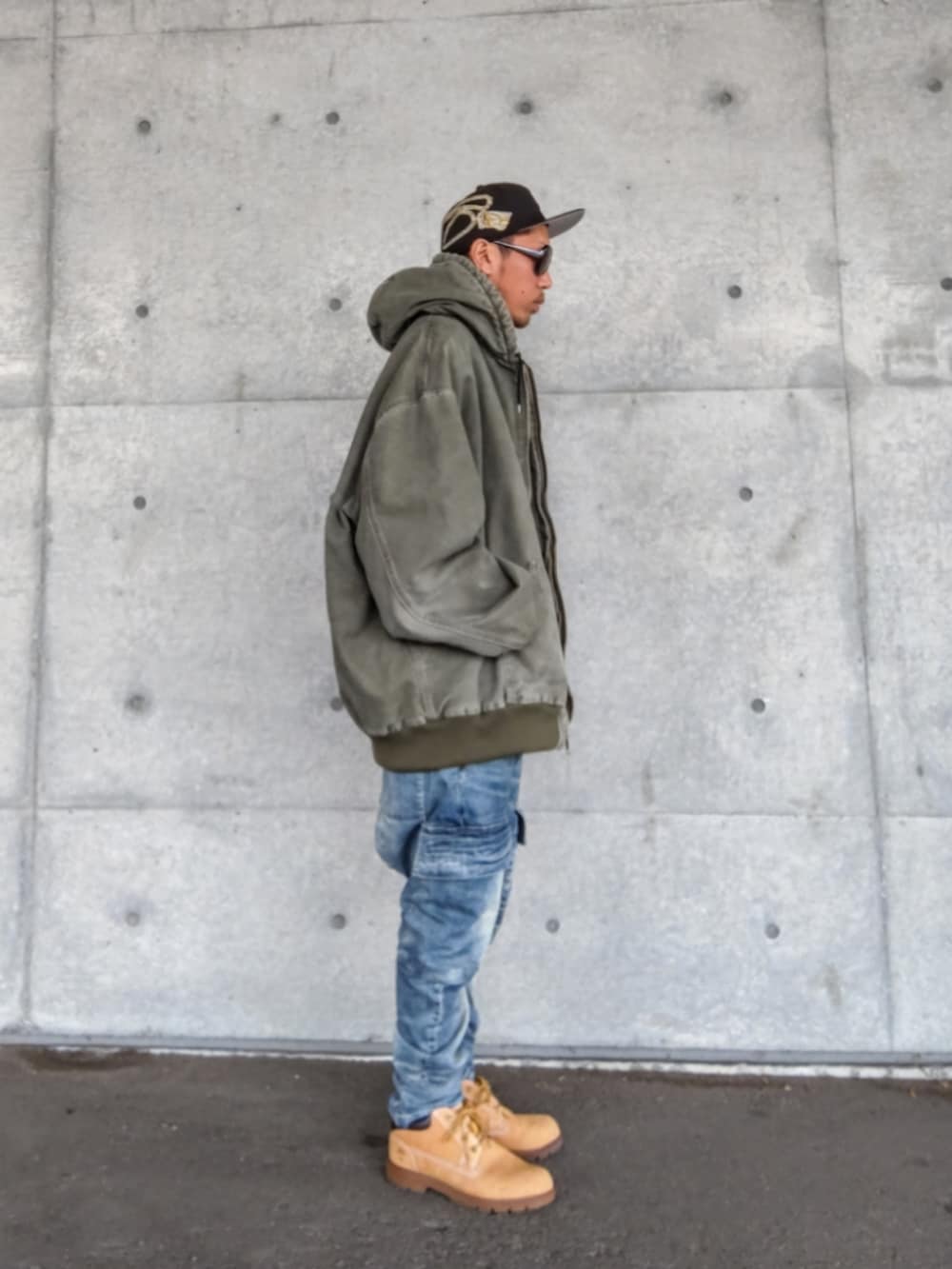 グリーン系のジャケット/アウター、ブラック系のTシャツ/カットソー、ブルー系のデニムパンツを着用したメンズの秋コーディネートの4枚目の写真