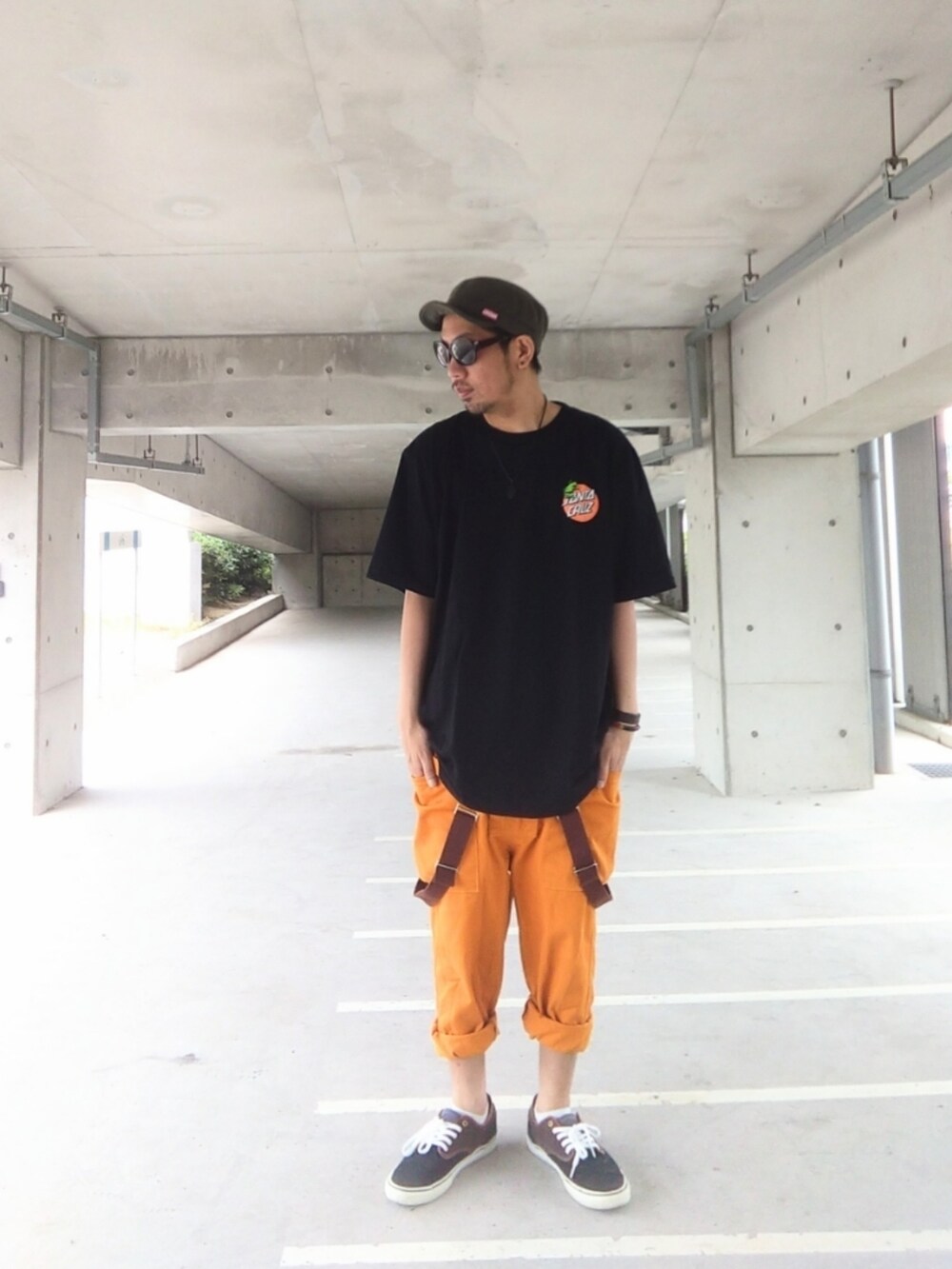 ブラック系のTシャツ/カットソー、オレンジ系のサロペット/オーバーオール、ブラック系のスニーカーを着用したメンズの夏コーディネートの2枚目の写真