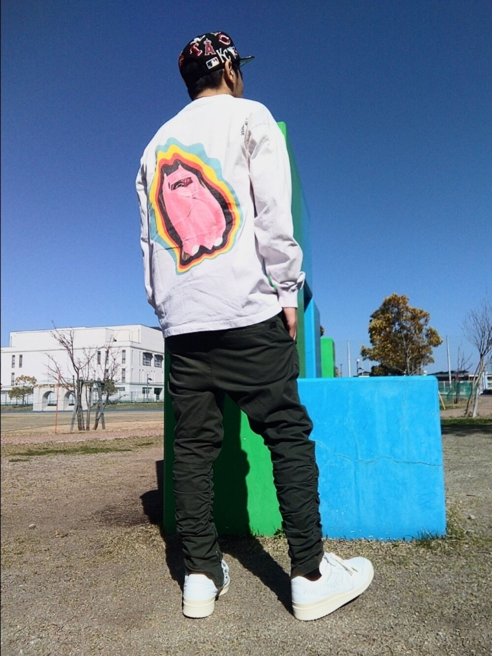 ピンク系のTシャツ/カットソー、グリーン系のパンツ、ホワイト系のスニーカーを着用したメンズの春コーディネートの3枚目の写真