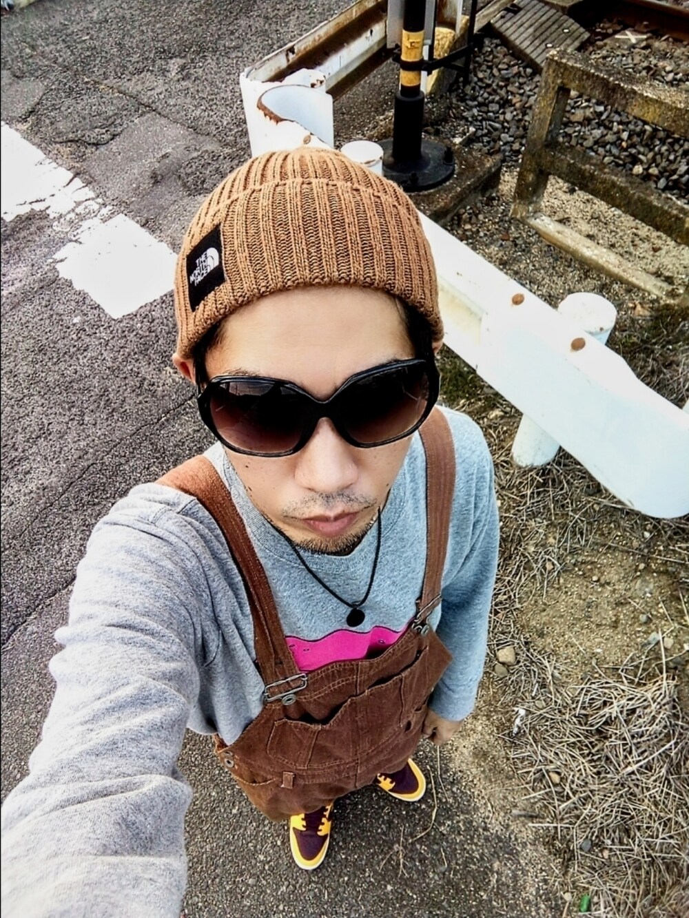 グレー系のスウェット、ブラウン系のサロペット/オーバーオール、イエロー系のスニーカーを着用したメンズの秋コーディネートの3枚目の写真