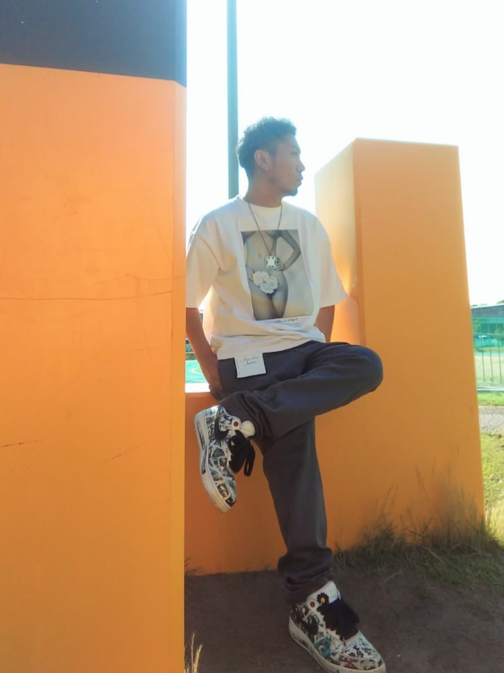 グレー系のチノパンツ、ホワイト系のスニーカー、ホワイト系のTシャツ/カットソーを着用したメンズの夏コーディネートの2枚目の写真