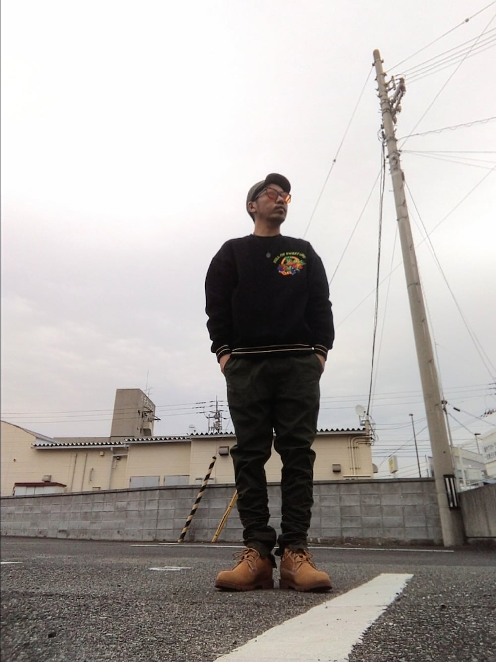 ブラック系のスウェット、グリーン系のパンツ、イエロー系のブーツを着用したメンズの秋コーディネートの2枚目の写真