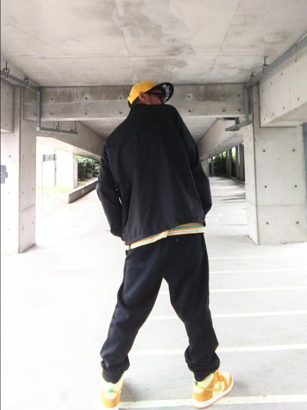 ブルー系のナイロンジャケット、イエロー系のTシャツ/カットソー、ブラック系のスウェットパンツを着用したメンズの秋コーディネートの3枚目の写真