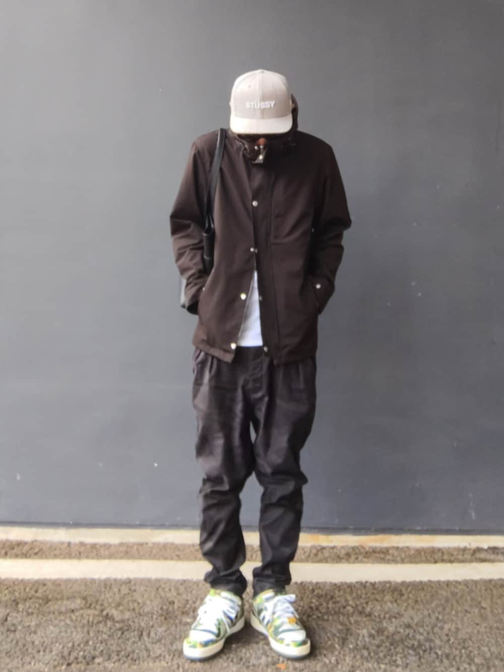 ブラック系のマウンテンパーカー、ブラック系のパンツ、グリーン系のスニーカーを着用したメンズの秋コーディネートの2枚目の写真