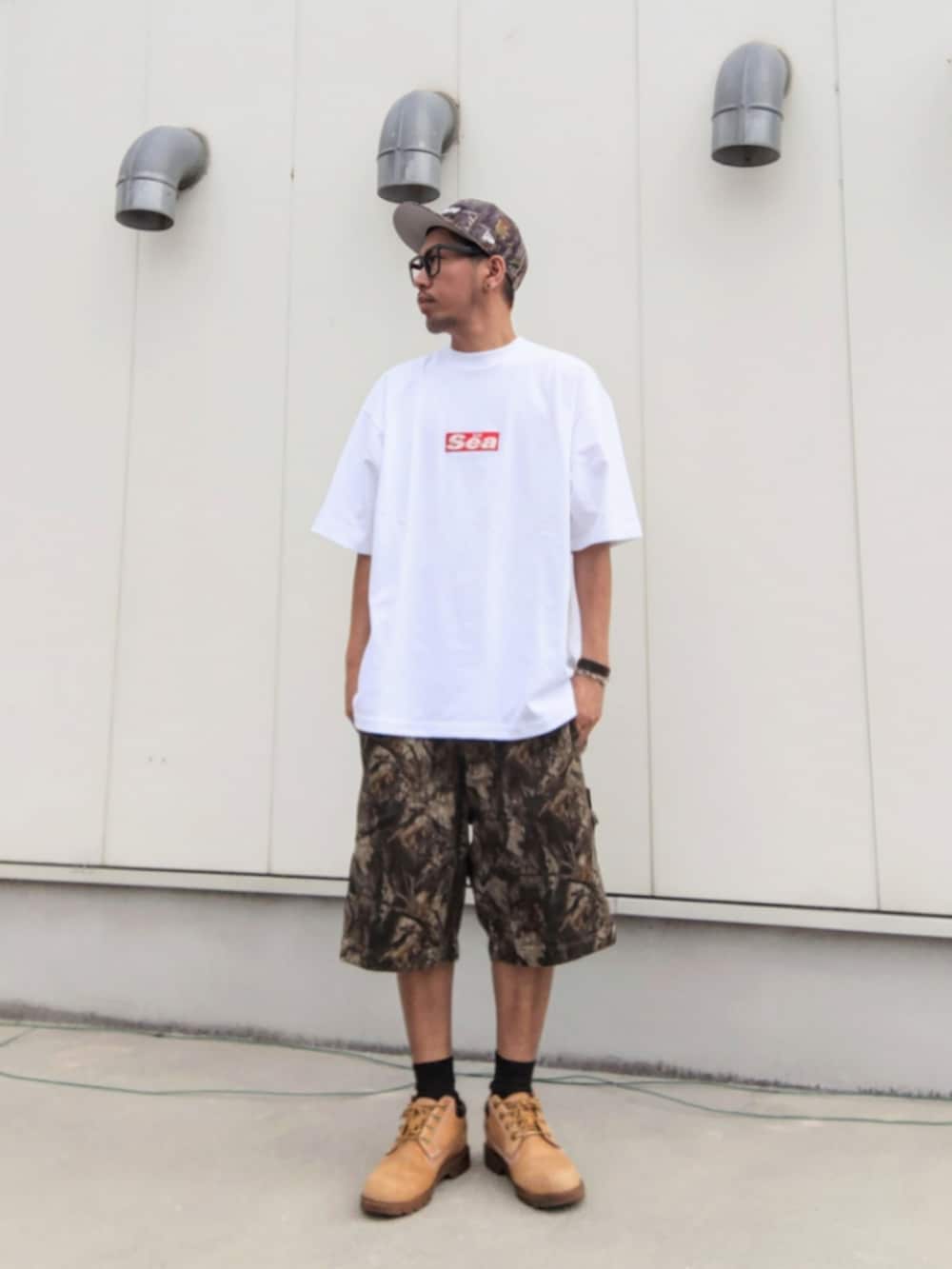 ホワイト系のTシャツ/カットソー、ブラウン系のその他パンツ、イエロー系のブーツを着用したメンズの夏コーディネートの2枚目の写真