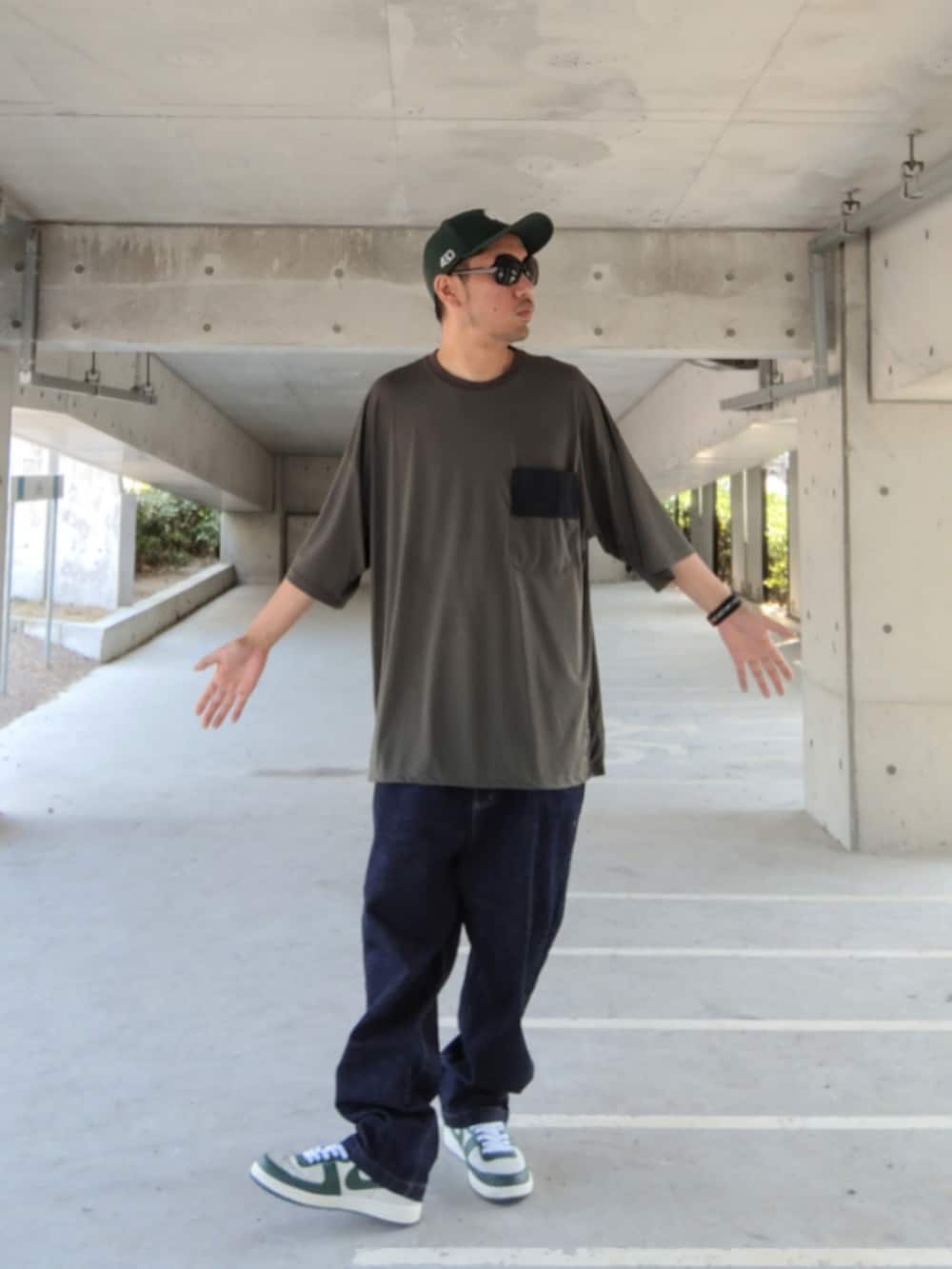 グリーン系のTシャツ/カットソー、ブルー系のデニムパンツ、ホワイト系のスニーカーを着用したメンズの夏コーディネートの2枚目の写真