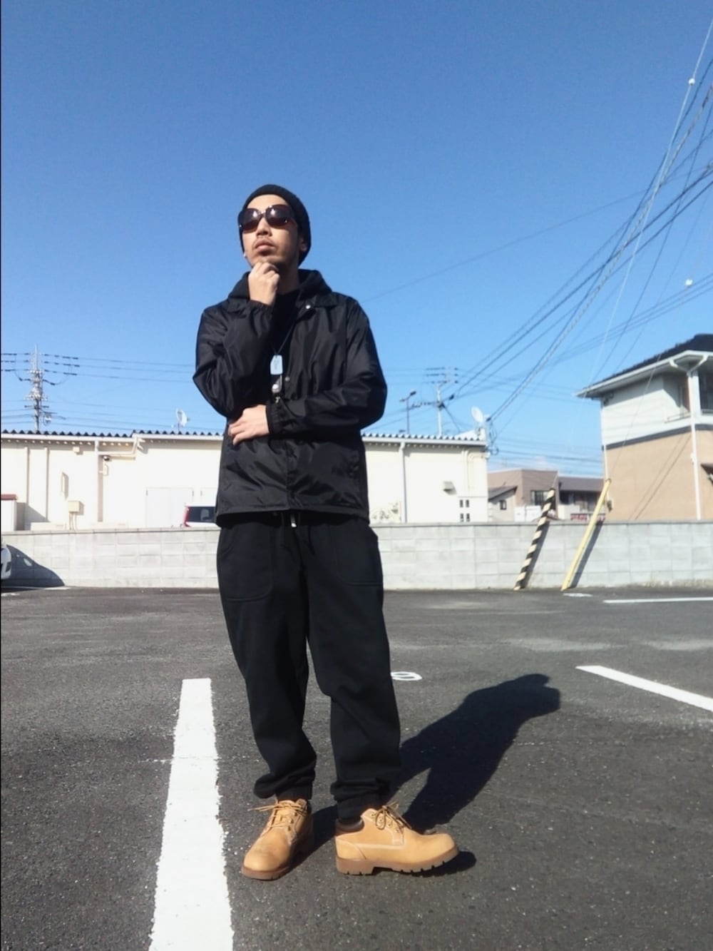 ブルー系のナイロンジャケット、ブラック系のパーカー、ブラック系のスウェットパンツを着用したメンズの春コーディネートの2枚目の写真