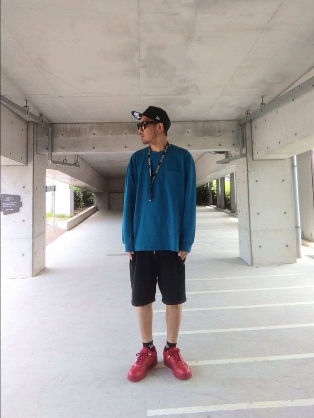 レッド系のスニーカー、ブルー系のトップス、ブラック系のその他パンツを着用したメンズの春コーディネートの2枚目の写真