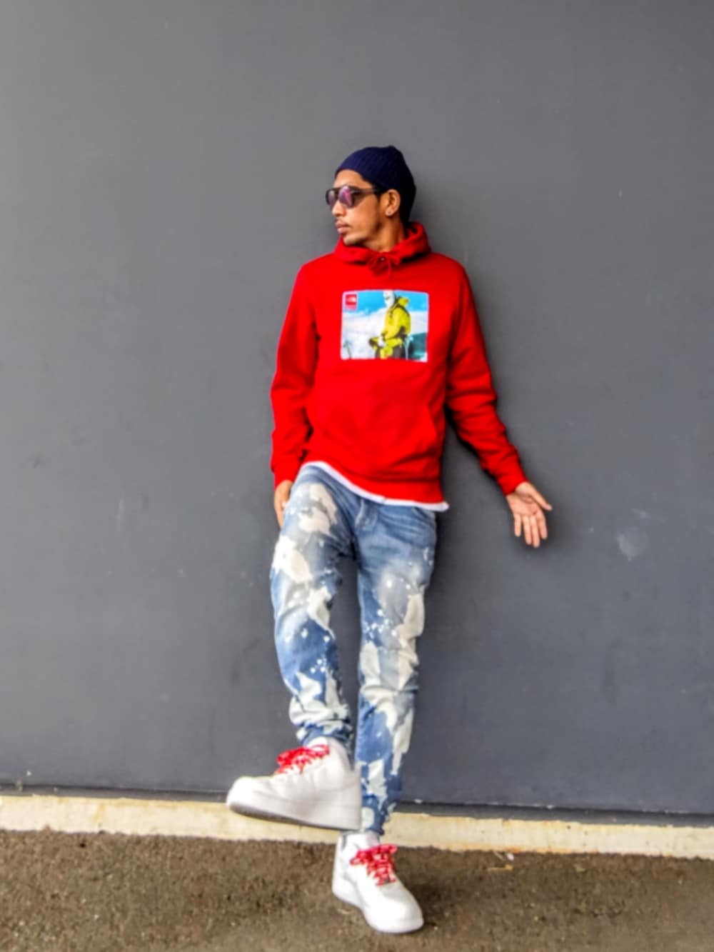 レッド系のパーカー、ブルー系のデニムパンツ、ホワイト系のスニーカーを着用したメンズの冬コーディネートの2枚目の写真