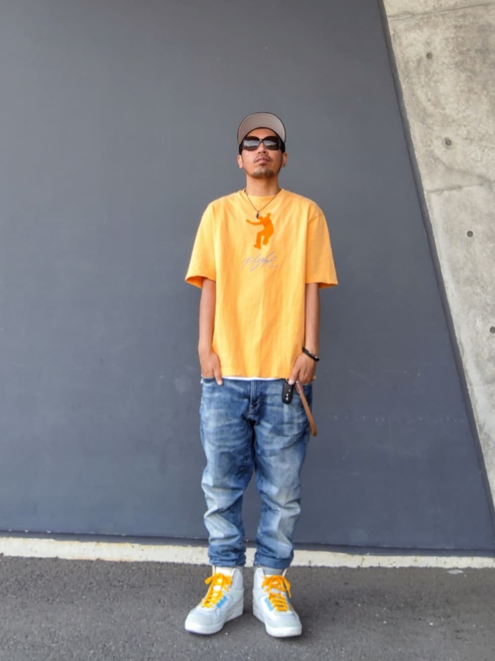 オレンジ系のTシャツ/カットソー、ホワイト系のタンクトップ、ブルー系のデニムパンツを着用したメンズの夏コーディネートの2枚目の写真