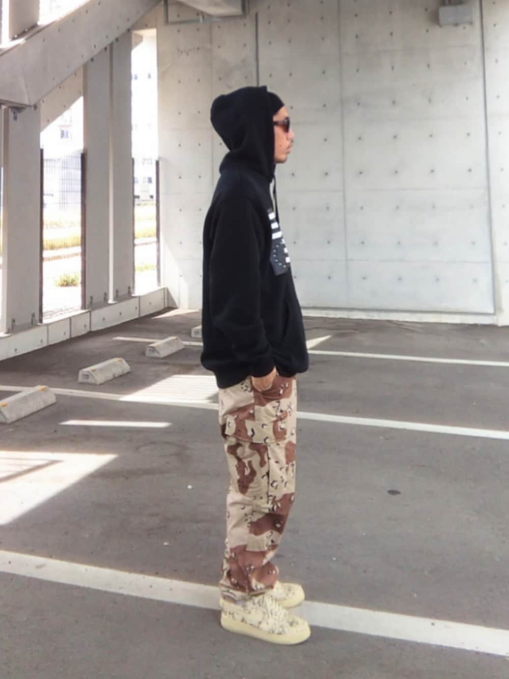 ブラック系のパーカー、その他のカーゴパンツ、ベージュ系のスニーカーを着用したメンズの春コーディネートの3枚目の写真