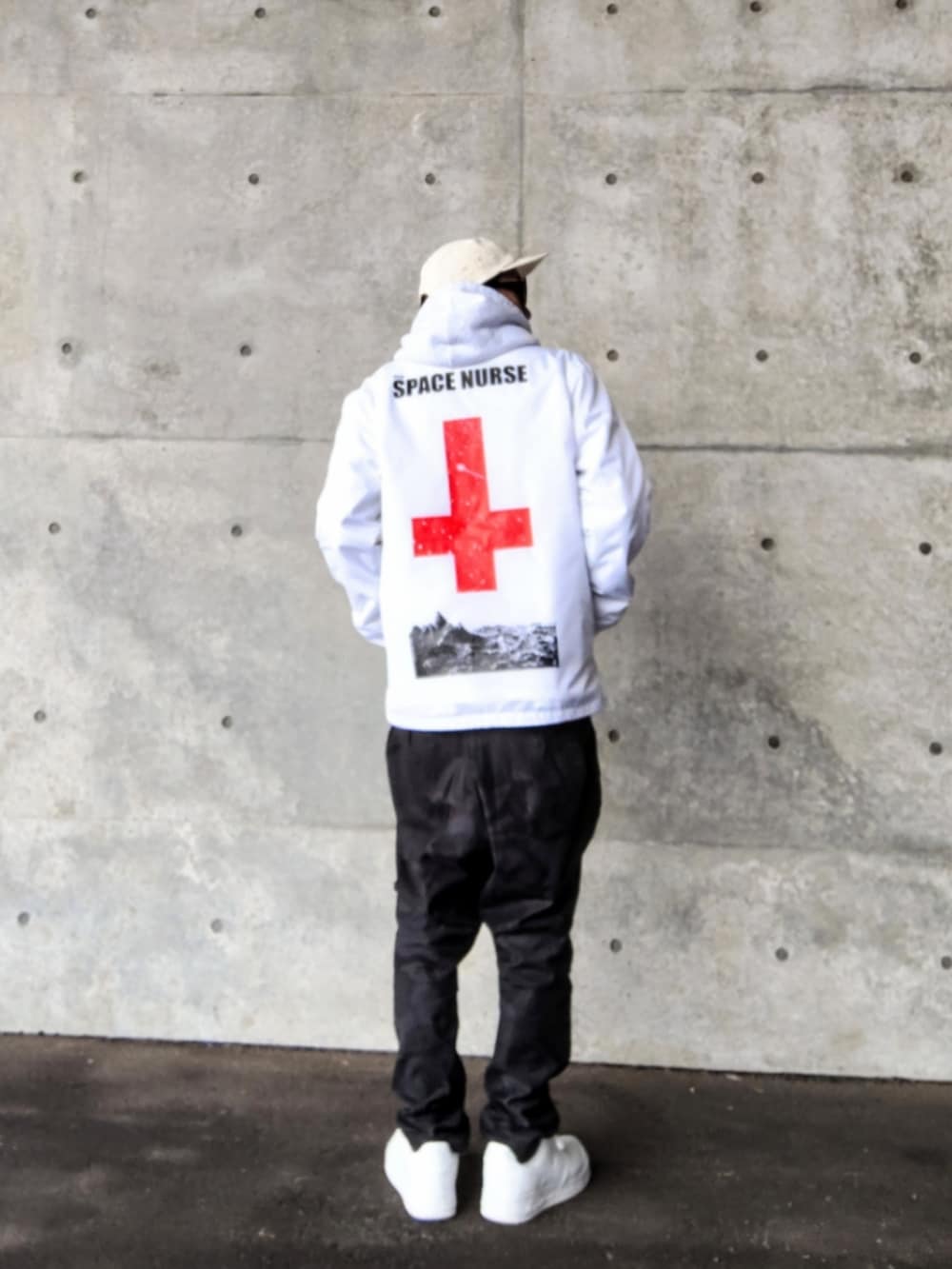 ホワイト系のナイロンジャケット、グレー系のパーカー、ブラック系のパンツを着用したメンズの春コーディネートの2枚目の写真