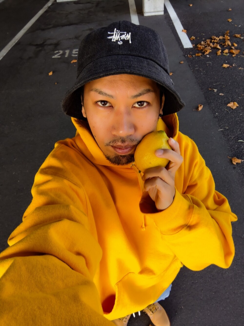 イエロー系のパーカー、ブルー系のデニムパンツ、イエロー系のブーツを着用したメンズの秋コーディネートの3枚目の写真