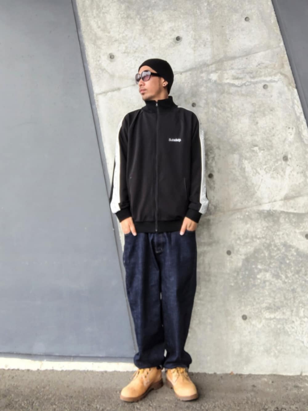 ブラック系のジャージ、ホワイト系のタンクトップ、ブルー系のデニムパンツを着用したメンズの春コーディネートの3枚目の写真