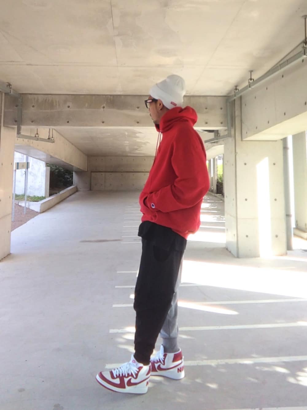 レッド系のパーカー、ブラック系のTシャツ/カットソー、その他のスウェットパンツを着用したメンズの秋コーディネートの2枚目の写真