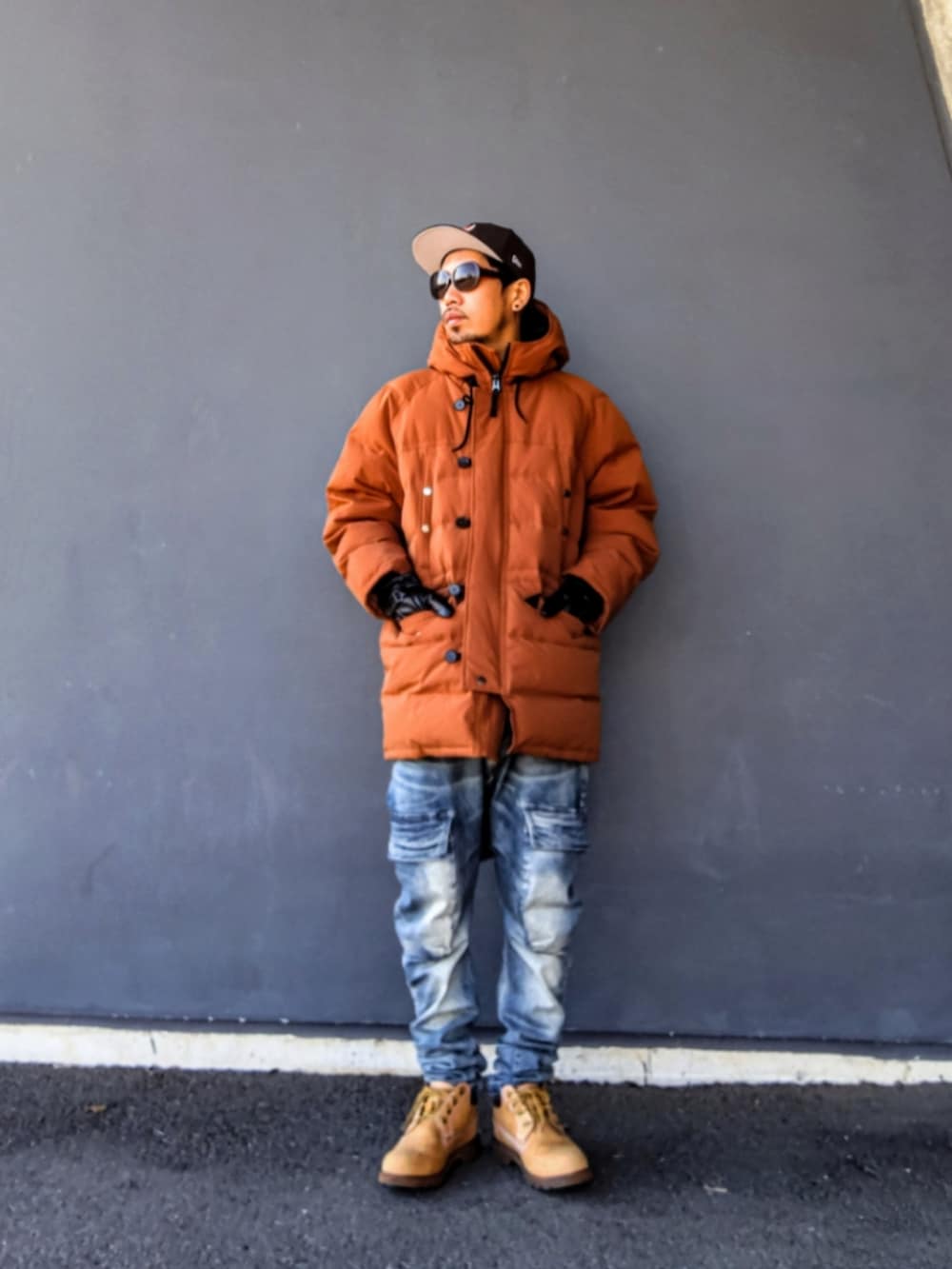 イエロー系のダウンジャケット/コート、ブルー系のデニムパンツ、イエロー系のブーツを着用したメンズの冬コーディネートの2枚目の写真