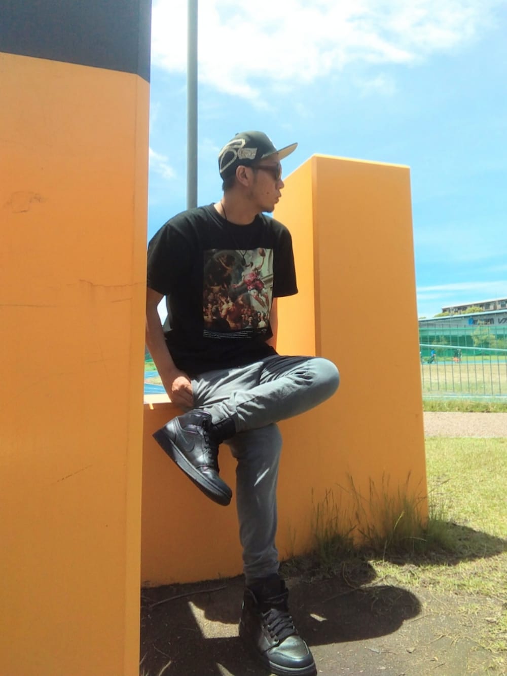 ブラック系のTシャツ/カットソー、ベージュ系のチノパンツ、ホワイト系のスニーカーを着用したメンズの夏コーディネートの3枚目の写真