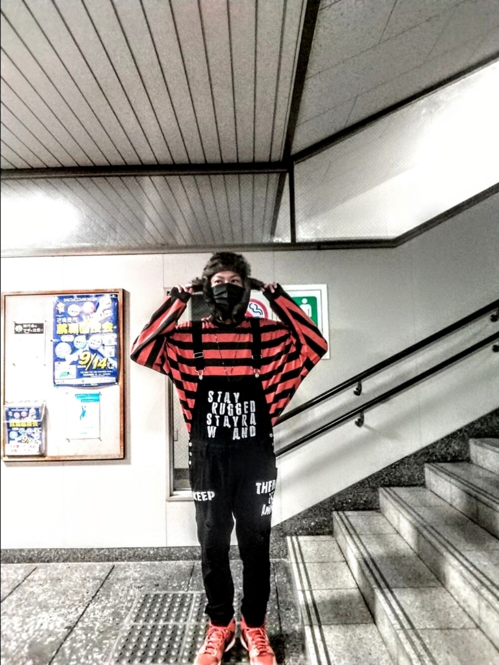 オレンジ系のニット/セーター、ブラック系のサロペット/オーバーオール、オレンジ系のスニーカーを着用したメンズの秋コーディネートの3枚目の写真