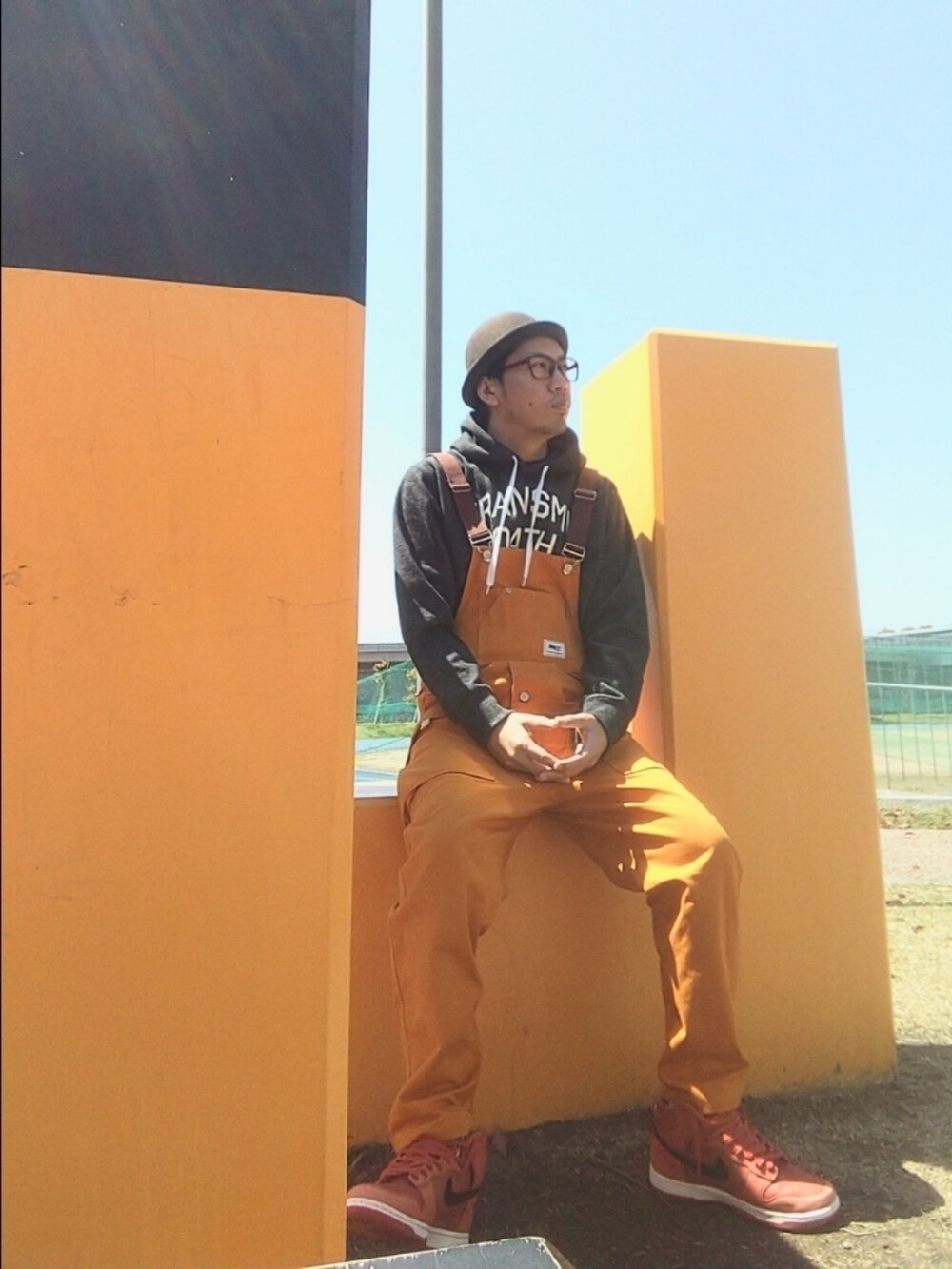 グレー系のパーカー、ブラウン系のサロペット/オーバーオール、オレンジ系のスニーカーを着用したメンズの春コーディネートの3枚目の写真