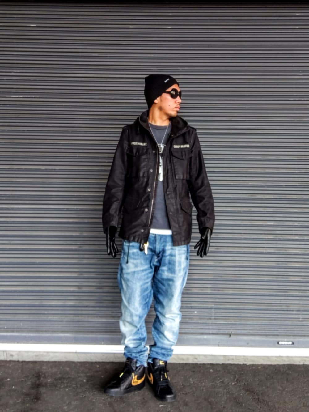 ブラック系のミリタリージャケット、グレー系のTシャツ/カットソー、ブルー系のデニムパンツを着用したメンズの秋コーディネートの2枚目の写真